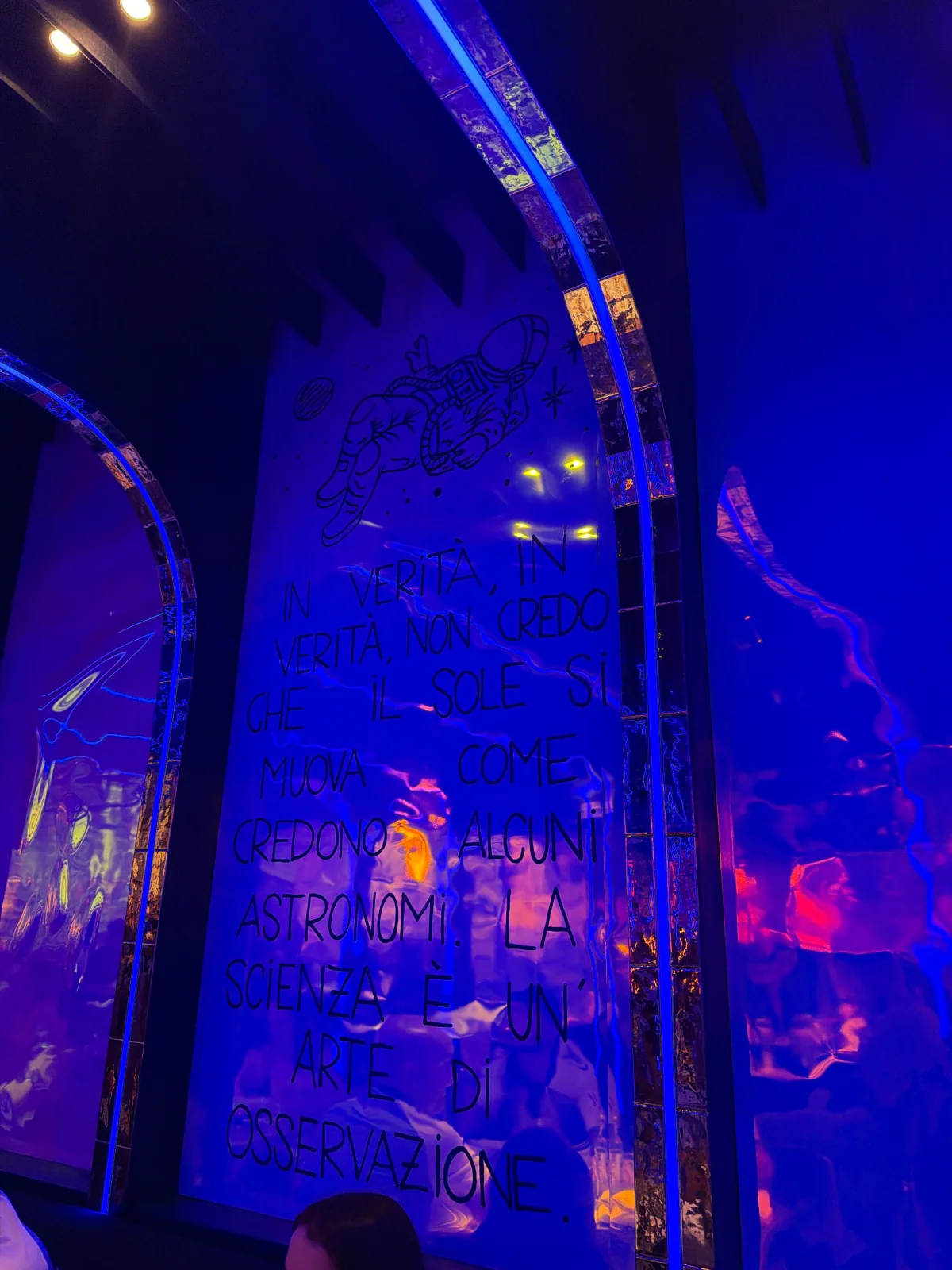 Electric-blue restaurant interior with mirrored arches and an astronaut mural